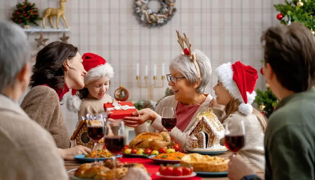 Happy Holidays and New Year family celebration gathered around a festive table sharing gifts and joyful moments